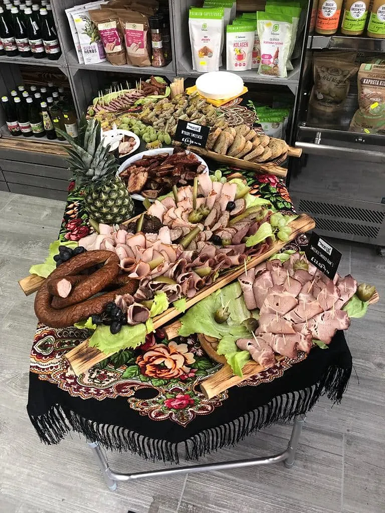 Proeftafel met Poolse vleeswaren, brood en augurken op een zwarte omslagdoek met rozen